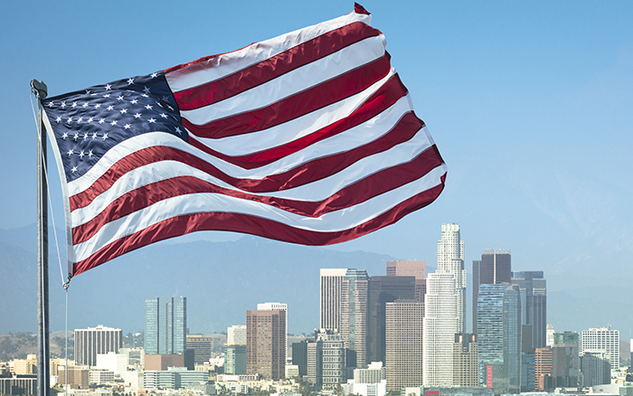 American Flag flying in fore-front with City of Los Angeles in background on sunny day